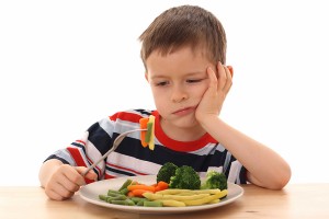 5-6 years old boy and plate of cooked vegetables isolated on white